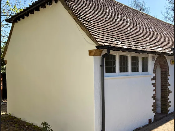 White rendered exterior of a Surrey property freshly painted against a blue sky by Goulds D&F