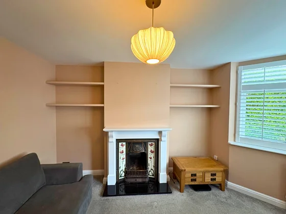 Freshly painted living room with warm peach walls, fireplace and alcove shelves by Goulds D&F