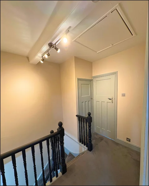 Freshly painted landing and hallway with dark balustrade and pale warm walls by Goulds D&F